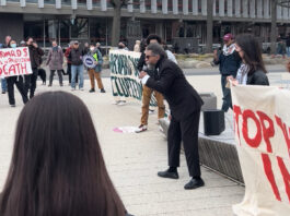 Cornel West (center, in black suit) speaking to a crowd of student activists in Harvard Science Center Plaza.