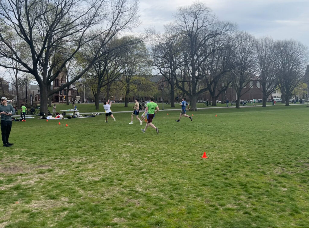 One player catches the ball ahead of two other players in Cambridge Common park.
