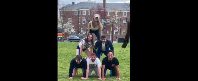 Six players stacked together in a human pyramid in Cambridge Common park.