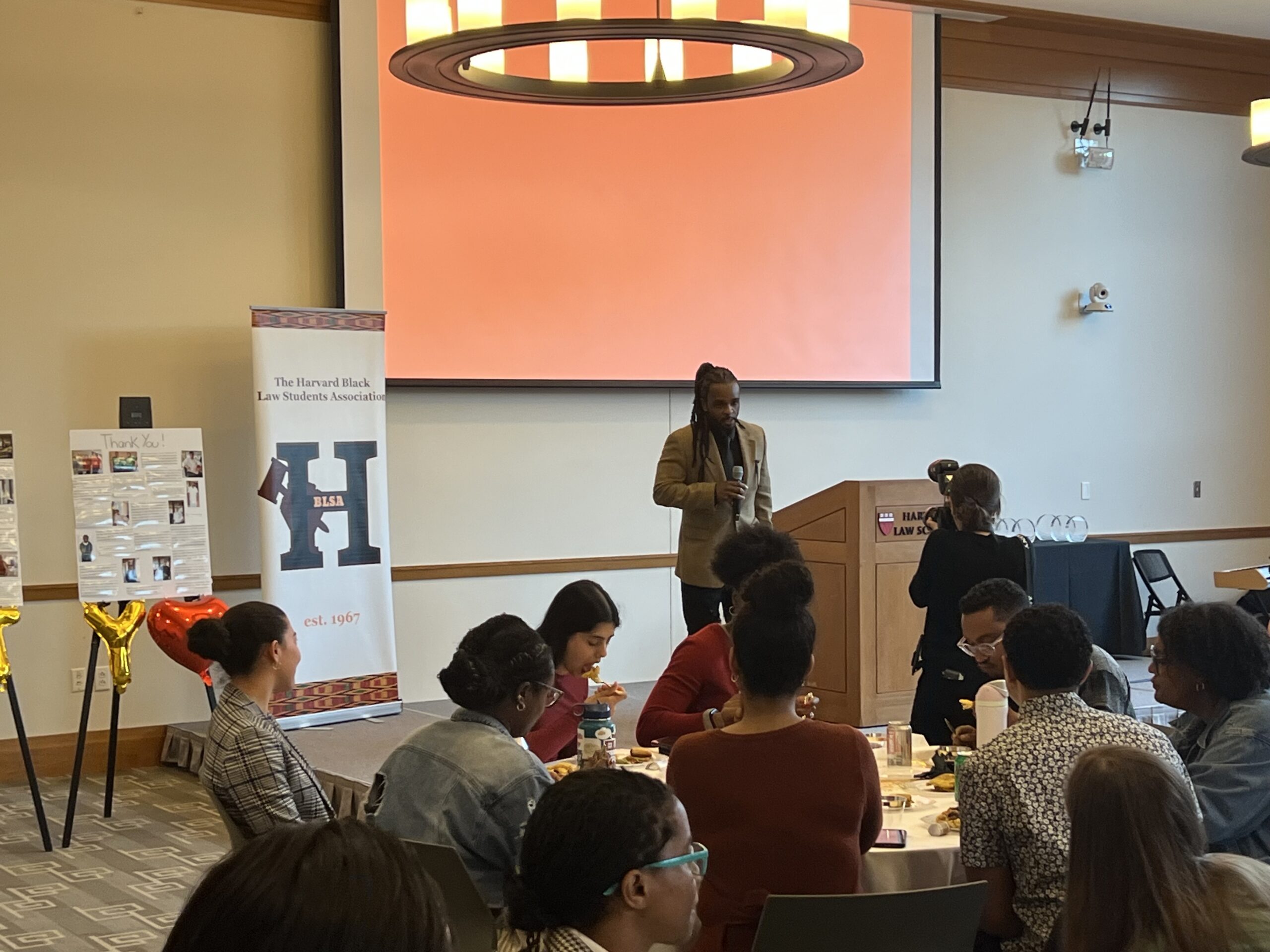 Brione Merchant stands at the front of Milstein, addressing a crowd.