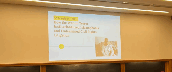 Presentation in a classroom in a Wasserstein hall section classroom reads "Ashcroft v. Iqbal: How the War on Terror Institutionalized Islamophobia and Undermined Civil Rights Litigation" (I. Bharmal, 2022).